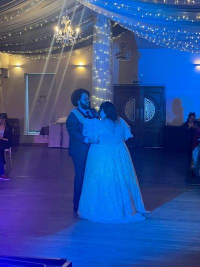 Newlyweds share their first dance beneath a fairy-lit canopy