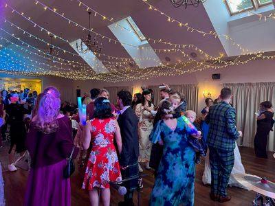 Guests fill a marquee under strings of festoon lights