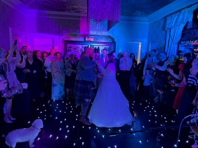 A bride dances in the middle of the ceilidh as guests cheer her on