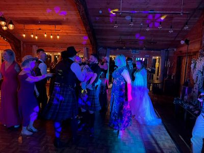 Kilted dancers spin through a ceilidh set under fairy lights