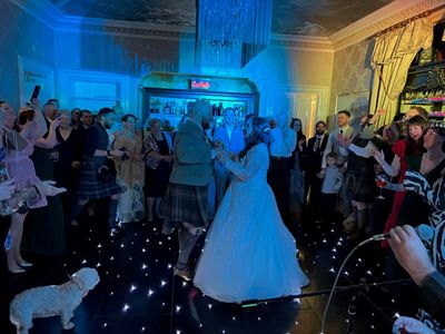 A bride dances surrounded by guests against a starlit backdrop