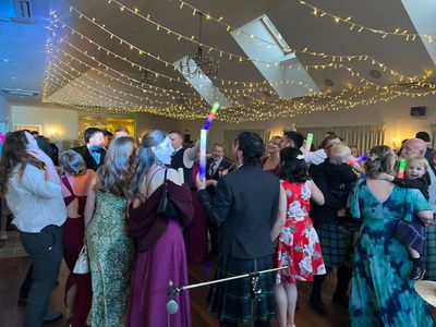 Guests link arms for a ceilidh dance under warm lights